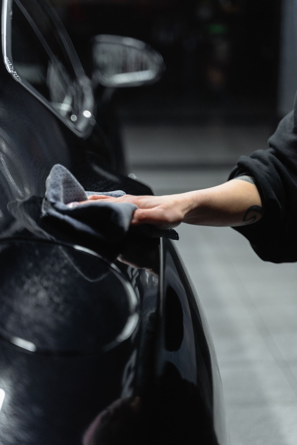 Close-up detail photography of a vehicle being gently cleaned with a microfiber cloth