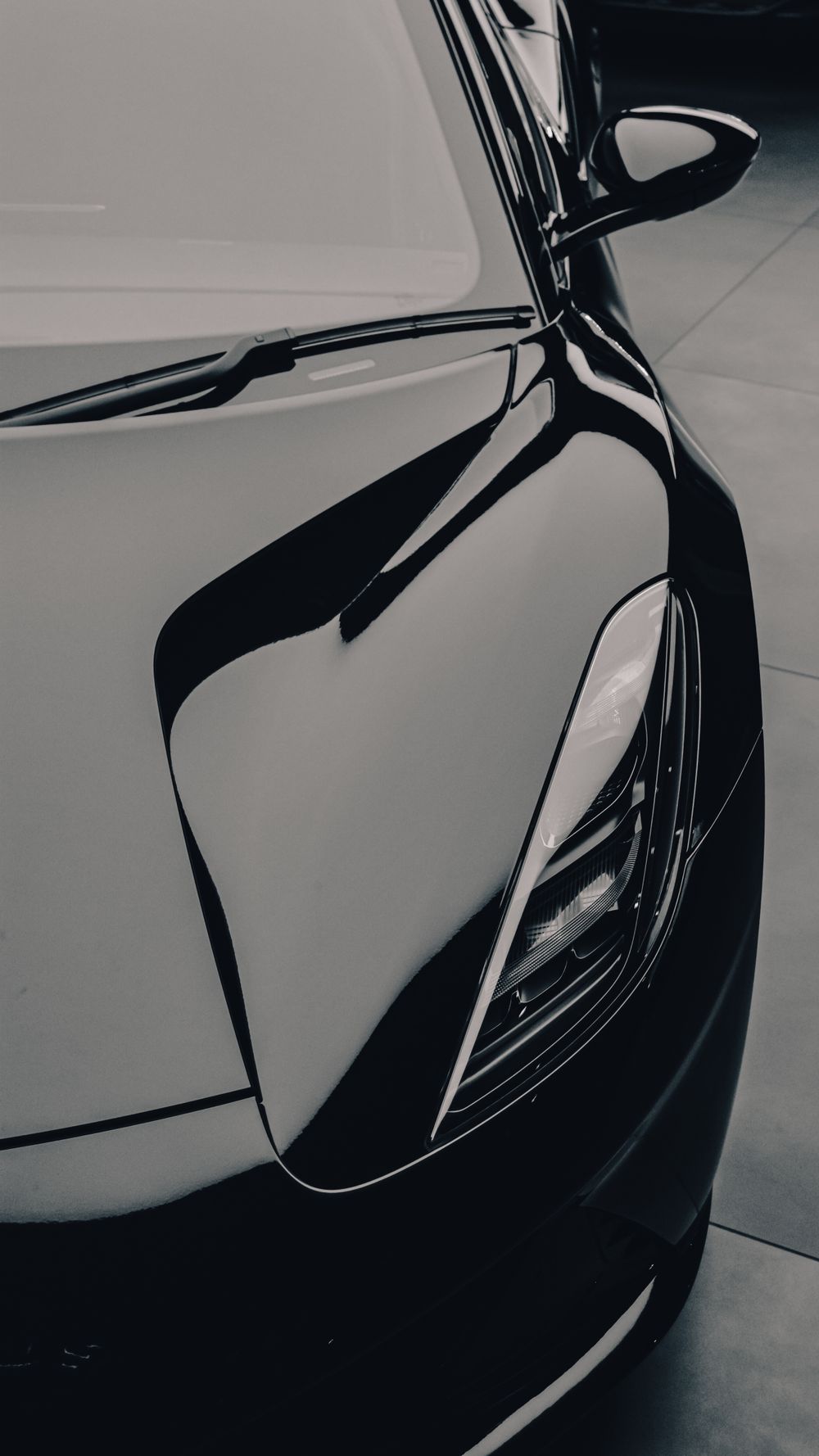 Sculptural close-up of a glossy dark vehicle's headlight