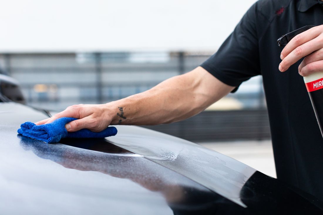 Detailed close-up of hands working on a vehicle's finish